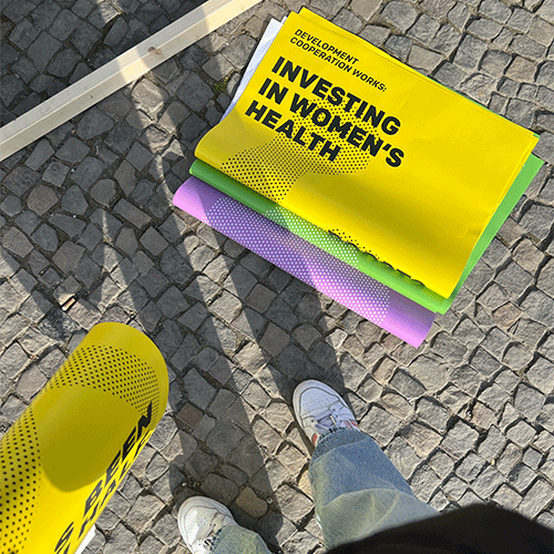 Investing in Women's Health — Plakatstapel auf Kopfsteinpflaster