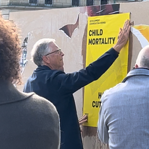 Bill Gates klebt ein ONE-Plakat in Berlin